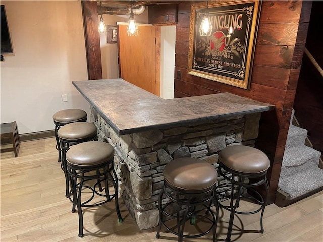 bar featuring light wood-style flooring, baseboards, and stairway