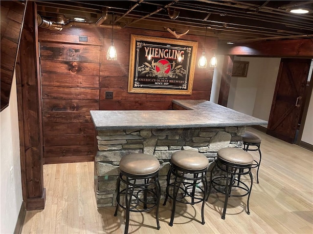 bar featuring indoor wet bar, light wood finished floors, and baseboards