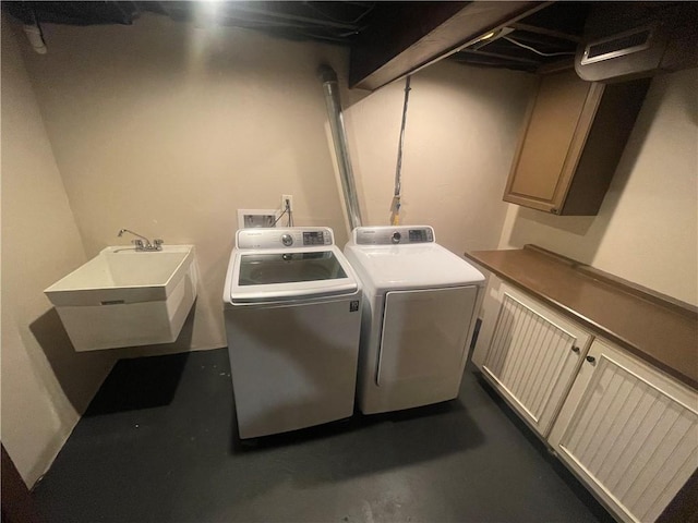 washroom featuring cabinet space, visible vents, washing machine and clothes dryer, and a sink