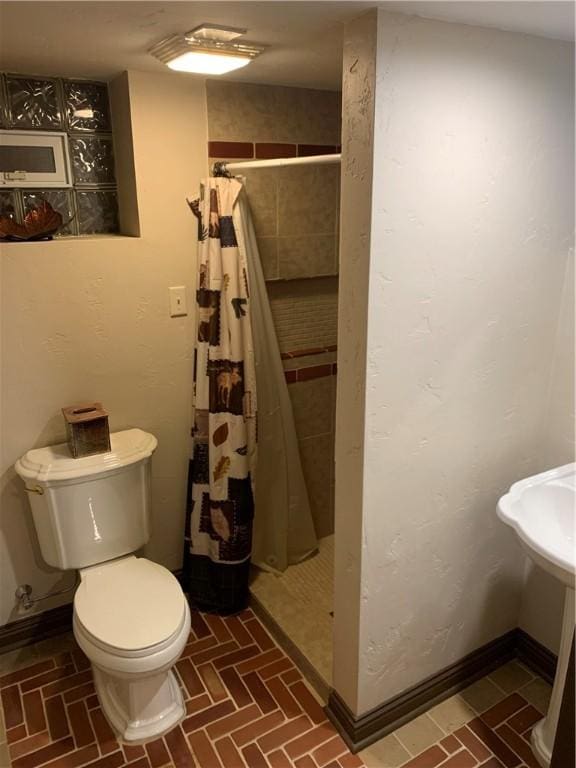 full bathroom with brick floor, toilet, and a stall shower