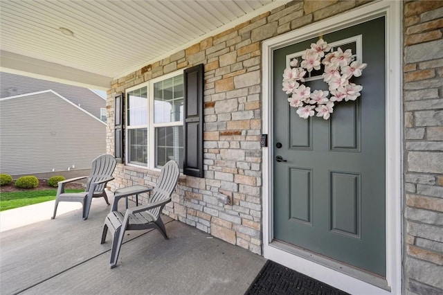 view of exterior entry with a porch and stone siding