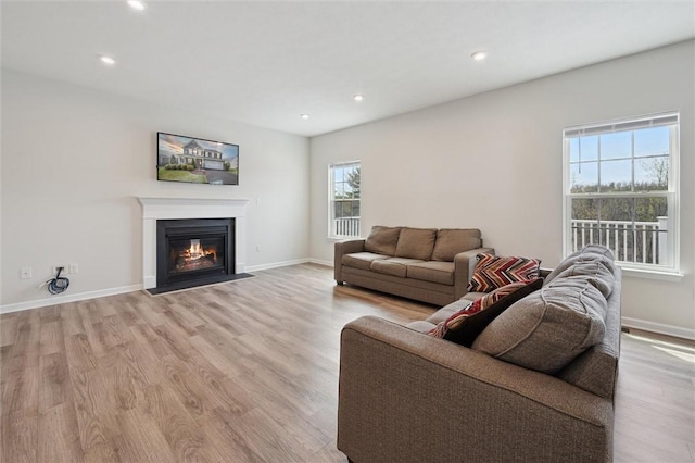 living room featuring a fireplace with flush hearth, baseboards, light wood finished floors, and recessed lighting