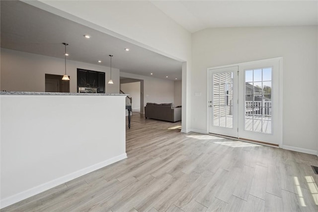 unfurnished living room with recessed lighting, light wood-style floors, vaulted ceiling, and baseboards