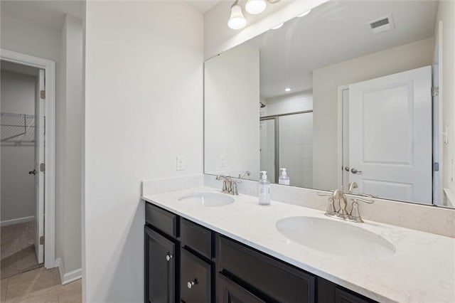 full bath featuring double vanity, a sink, visible vents, and a stall shower