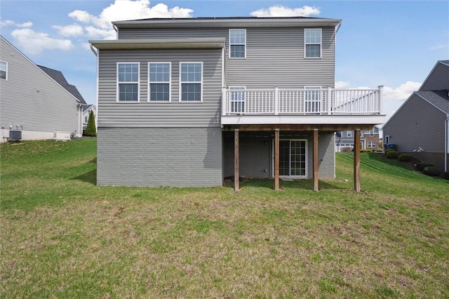 back of property with a wooden deck, a yard, and brick siding