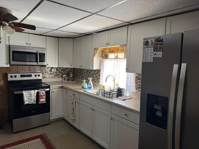 kitchen with a sink, backsplash, a ceiling fan, light countertops, and appliances with stainless steel finishes