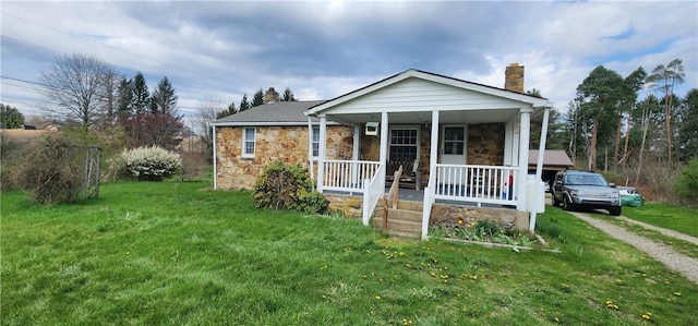 bungalow featuring a front lawn, stone siding, a chimney, covered porch, and dirt driveway