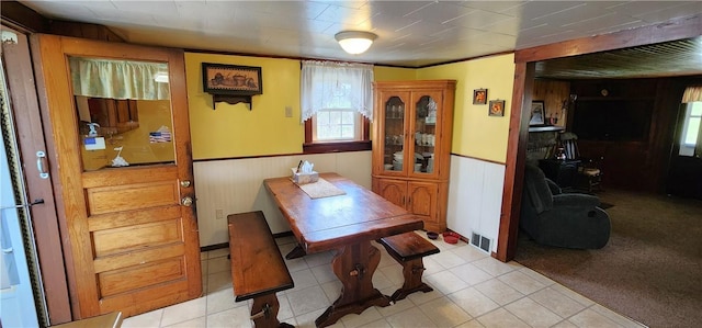 dining room featuring wainscoting, wood walls, and light tile patterned floors