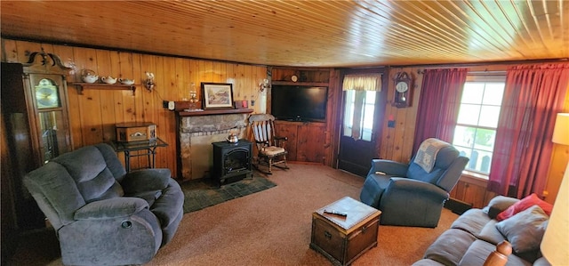living room with wood ceiling, wood walls, a wood stove, and carpet