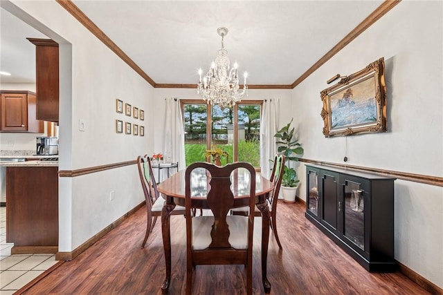dining space with wood finished floors, crown molding, baseboards, and a notable chandelier