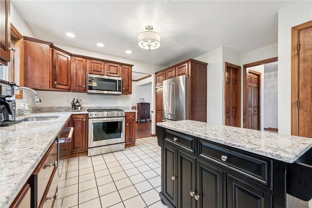 kitchen with a sink, light tile patterned floors, stainless steel appliances, light stone countertops, and recessed lighting