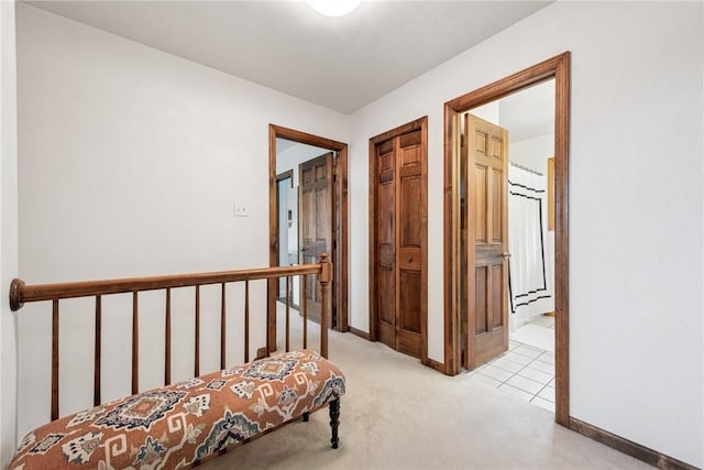 hall with light colored carpet, baseboards, and an upstairs landing