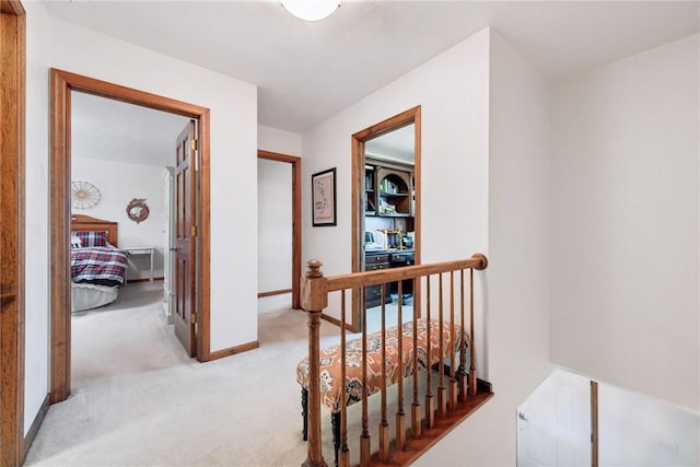 hall with baseboards, light carpet, and an upstairs landing
