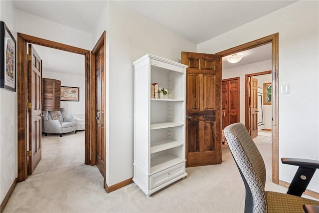 hall featuring light colored carpet and baseboards