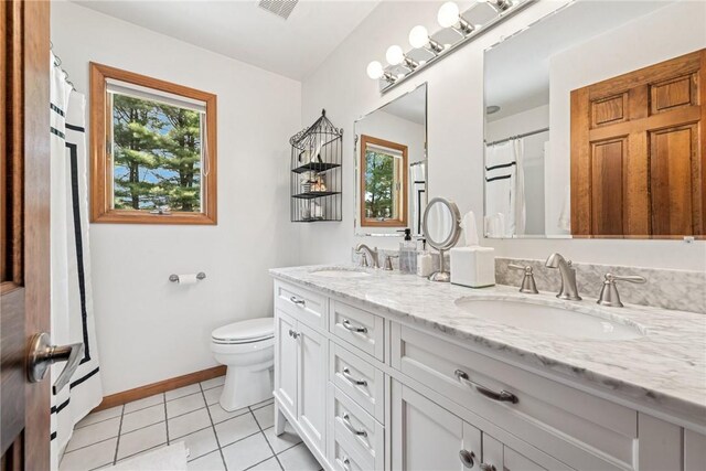bathroom with tile patterned flooring, baseboards, a sink, and toilet