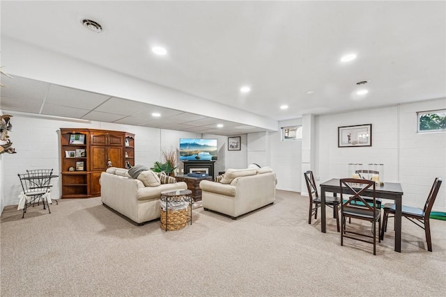 living room featuring visible vents, concrete block wall, a glass covered fireplace, and carpet floors