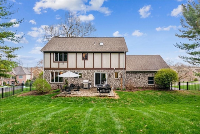 back of house with a yard, a patio area, stone siding, and a fenced backyard
