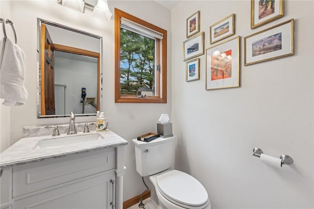 bathroom featuring baseboards, vanity, and toilet