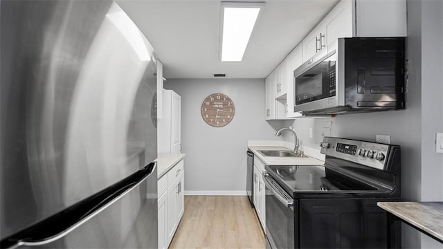5619 Kentucky Ave Unit 102, Shadyside, PA 15232 - kitchen with stainless steel appliances, a sink, light wood-style flooring, and white cabinetry