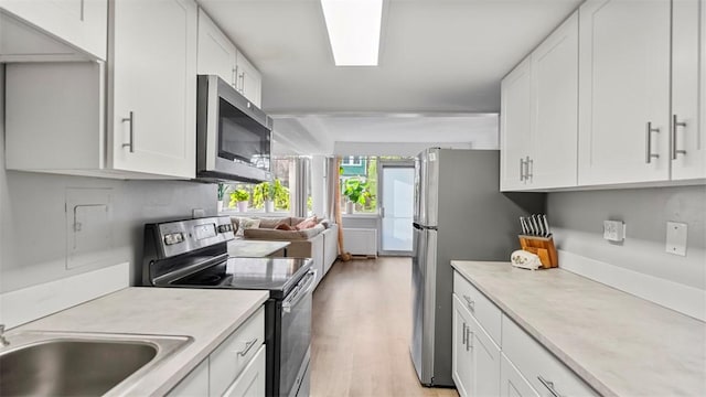kitchen featuring appliances with stainless steel finishes, white cabinetry, and light countertops
