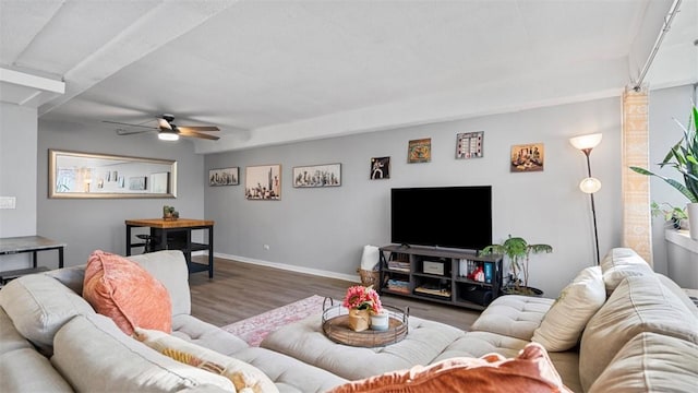 living area with wood finished floors, a ceiling fan, and baseboards