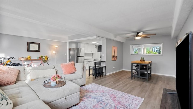 living room with light wood-style flooring, baseboards, and ceiling fan