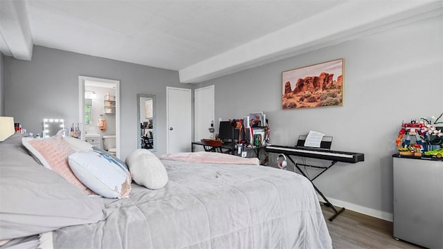bedroom with wood finished floors, ensuite bath, and baseboards