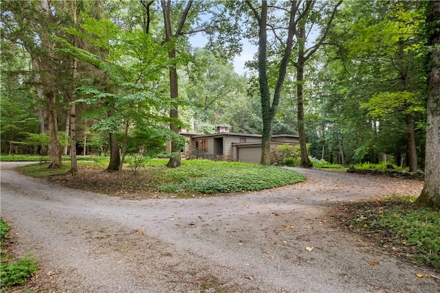 view of front facade featuring a garage, driveway, and a chimney