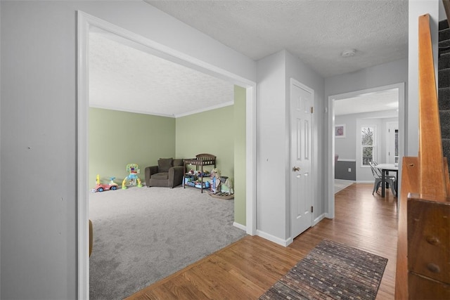 hall with a textured ceiling, wood finished floors, and baseboards