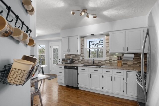 216 Briar Path, North Fayette, PA 15126 - kitchen featuring appliances with stainless steel finishes, a sink, decorative backsplash, dark wood-type flooring, and a textured ceiling