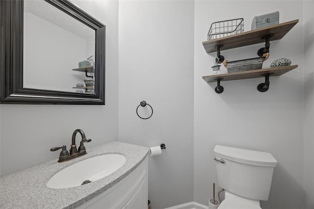 bathroom with toilet, vanity, and baseboards