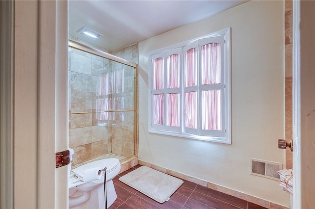 bathroom featuring toilet, a shower stall, and baseboards