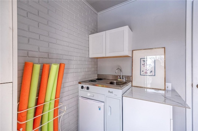 laundry area featuring a sink, ornamental molding, and brick wall