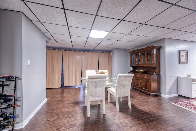 dining area with dark wood-type flooring, baseboards, and a paneled ceiling