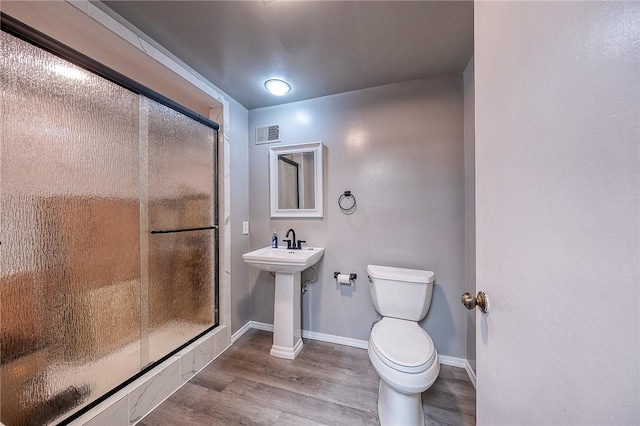 bathroom featuring wood finished floors, toilet, a shower stall, and baseboards