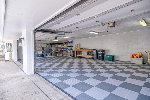 garage featuring a garage door opener and concrete block wall