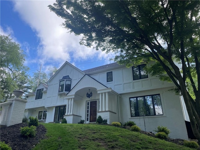 english style home with a front yard and stucco siding