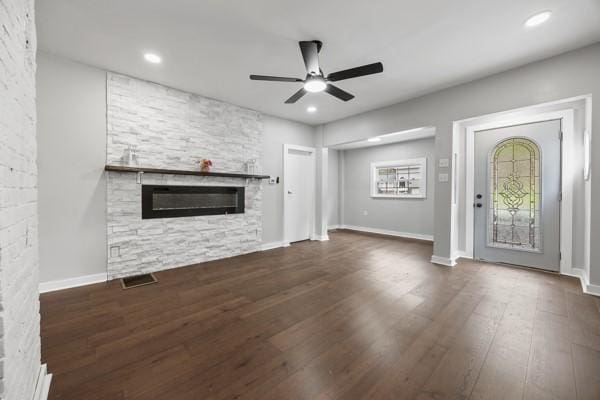unfurnished living room with a fireplace, a ceiling fan, visible vents, baseboards, and wood finished floors