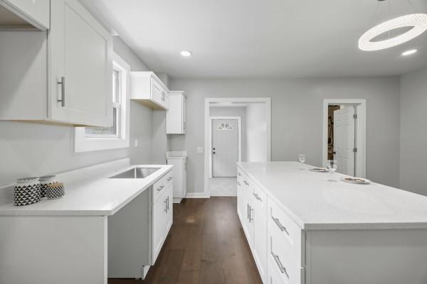 kitchen featuring recessed lighting, light countertops, a kitchen island, white cabinetry, and dark wood-type flooring