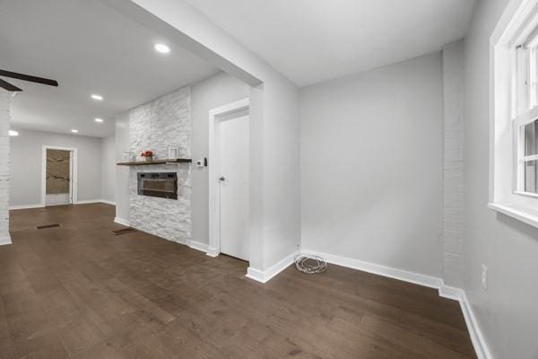 unfurnished living room with a fireplace, ceiling fan, wood finished floors, and baseboards