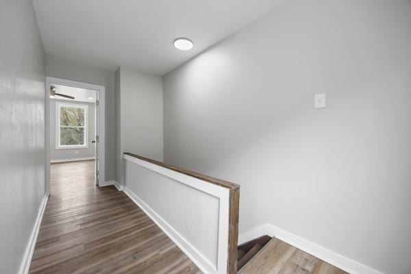 hall featuring an upstairs landing, wood finished floors, and baseboards