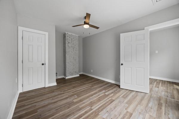 unfurnished bedroom featuring a ceiling fan, wood finished floors, and baseboards