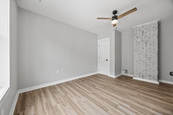 empty room featuring baseboards, visible vents, wood finished floors, and a ceiling fan