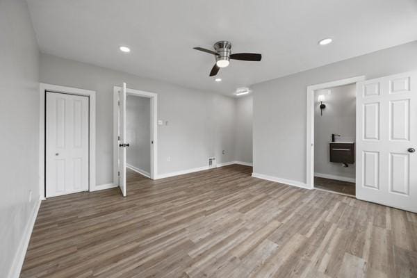 unfurnished bedroom featuring wood finished floors, ensuite bathroom, and baseboards