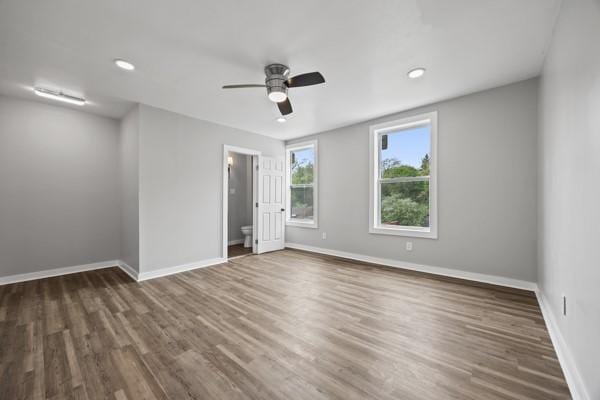unfurnished bedroom with ensuite bathroom, baseboards, recessed lighting, wood finished floors, and a ceiling fan
