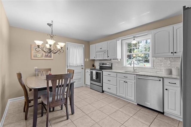 3216 Postgate Dr, Bethel Park, PA 15102 - kitchen with backsplash, light tile patterned floors, a sink, a chandelier, and appliances with stainless steel finishes