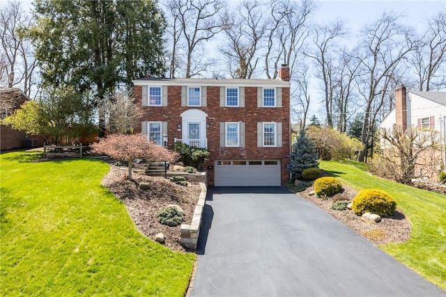 3216 Postgate Dr, Bethel Park, PA 15102 - colonial-style house featuring brick siding, an attached garage, aphalt driveway, and a front lawn