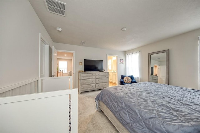 bedroom with visible vents, light colored carpet, and connected bathroom