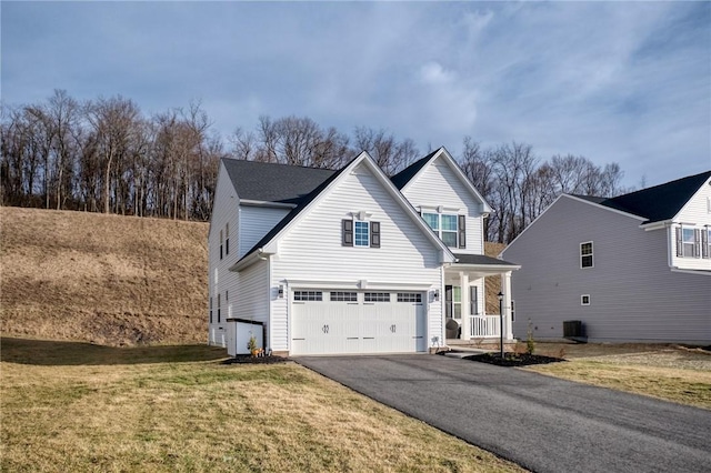 view of front of home featuring driveway, central AC, a front lawn, and a garage