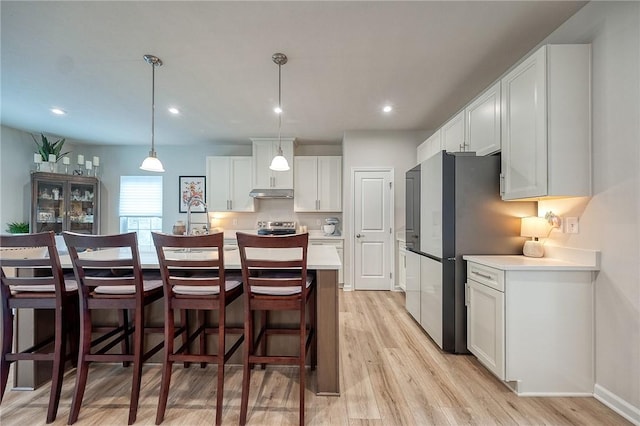 kitchen with white cabinets, light wood-type flooring, under cabinet range hood, and light countertops